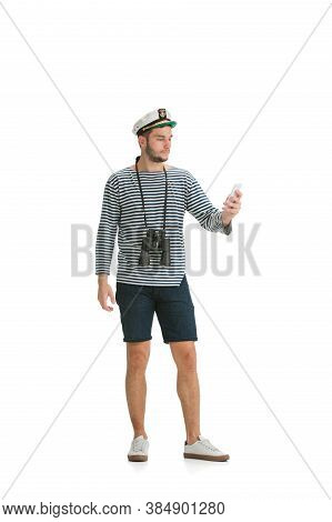 Scrolling Phone. Caucasian Male Sailor In Uniform On White Studio Background. Young Man Using Modern