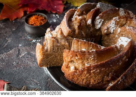 Bundt Cake With Saffron And Rum Covered With White Glaze On Rustic Background With Autumn Decoration