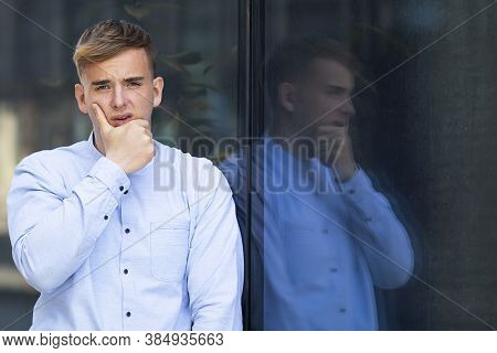 Portrait Of An Upset Handsome European Guy Holding His Chin Or Face, Formally Dressed In A White Shi