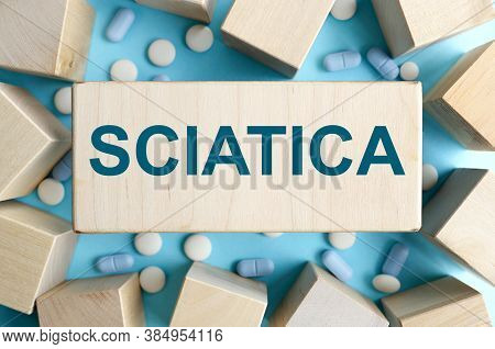 Sciatica. Text On A Wooden Block, Breaking Into Cubes, On A Blue Background