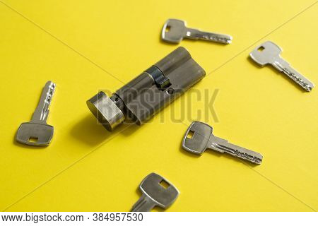 A Door Lock Cylinder Core With Keys On The Yellow Background. The Cylinder Of The Lock With Keys. In