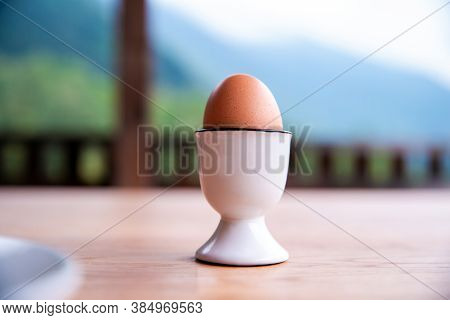 Boiled Egg In Eggcup On Wooden Table Outside, Breakfast Eggin White Egg Cup