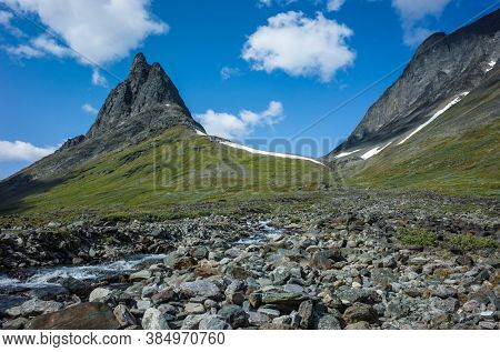Hiking in picturesque Swedish Lapland landscape. Nallo mountain in northern Sweden. Arctic environment of Scandinavia in summer sunny day with fluffy clouds