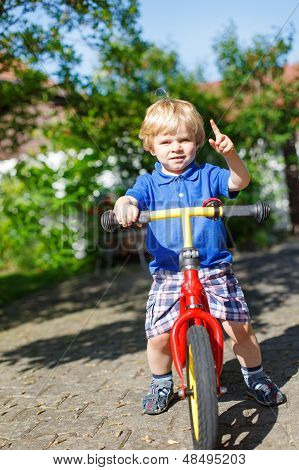 Ragazzino Toddler equitazione sulla sua bicicletta In estate