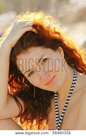 Beautiful young redhead woman smiling and running her hands in her hair