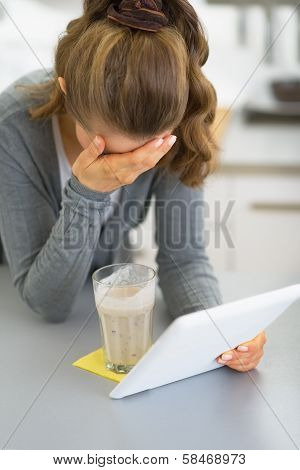 Stressed Young Woman With Tablet Pc In Kitchen