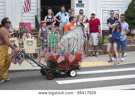 Man pushing giant oyster in the Wellfleet 4th of July Parade in Wellfleet, Massachusetts.