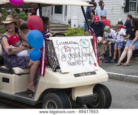 Woman rides in a golf cart in the Wellfleet 4th of July Parade in Wellfleet, Massachusetts