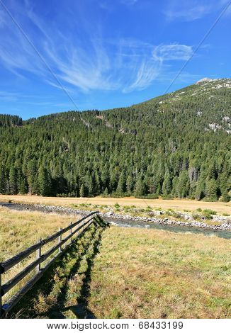 National Park Krimml. Scenic farm fields blocked bythe wooden fence. Shadow of the low fence beautifully lie on the grass. Alpine Valley in Austria
