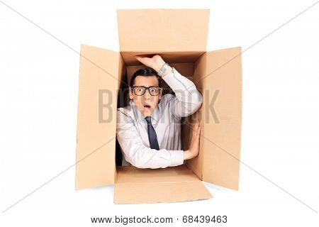 Young businessman trapped in a box isolated on white background
