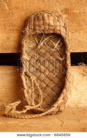 Vita rurale ancora. Scarpe bast tradizionale russo sullo sfondo delle tavole. Formato verticale.