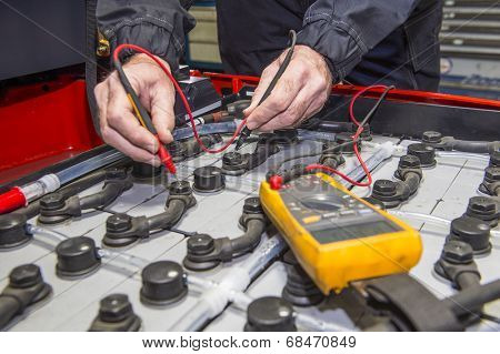 Man, checking the nodes of the battery pack of a forklift, using a multimeter