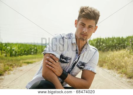 Handsome Young Man Sitting In Coutryside Dirt Road