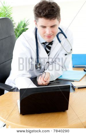 Asertivní muž lékař s notebookem u stolu