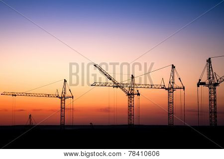 construction site with cranes against a sunset sky