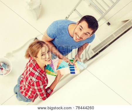 repair, interior design, building, renovation and home concept - smiling couple looking at color samples at home
