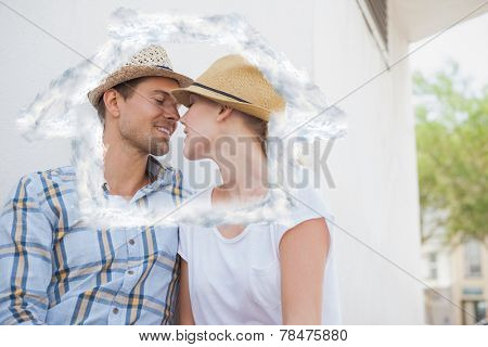 Young hip couple sitting on bench about to kiss against house outline in clouds