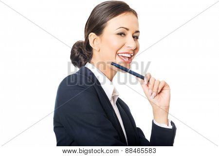 Portrait of businesswoman holding pen under chin, looking at the camera.