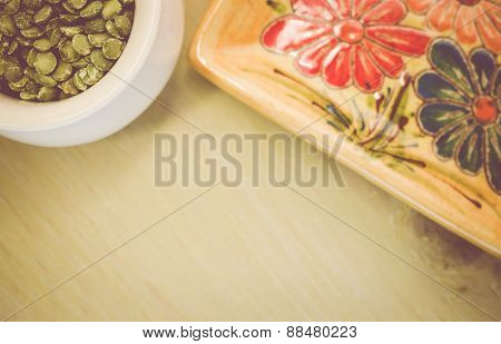 Yellow Porcelain Tablemat And Dried Pease On A Pastel Green Background