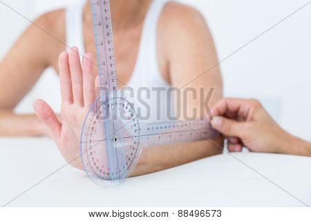 Doctor measuring wrist with goniometer in medical office