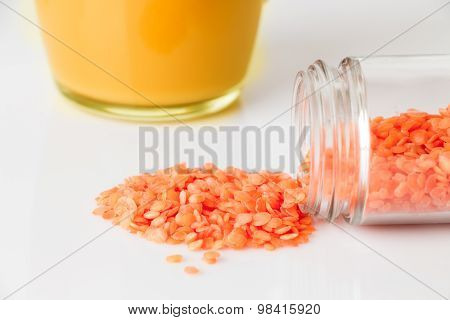 Orange lentils scattered from glass jar