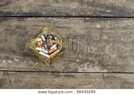 Ashtray Full Of Butt Cigarettes On Wooden Background