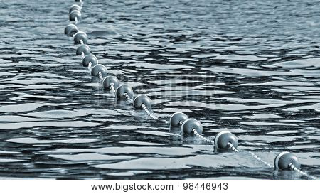 Buoys strung together by rope along lake to create safe swimming area for swimmers