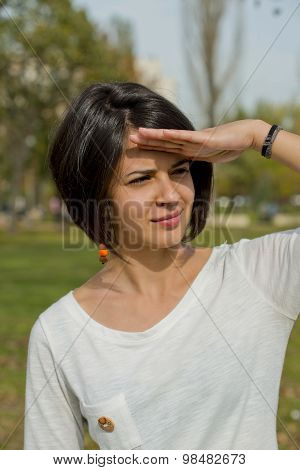 Portrait of a beautiful young woman holding hand on her forehead at autumn.