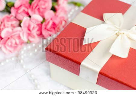 Close Up Of Gift Box With Pearl Necklace And Pink Carnation Flower On White Fur