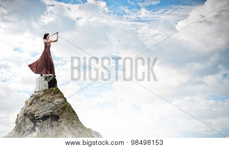 Young woman in evening dress wearing blindfold and playing fife