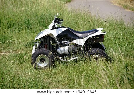 A quad terrain vehicle standing on a meadow in the field.