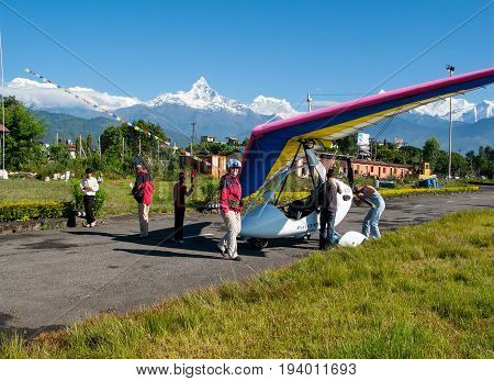 HIMALAYAS, POKHARA, NEPAL. 28 September 2008: Foreign tourist prepares for flight on a hang glider (deltaplan).