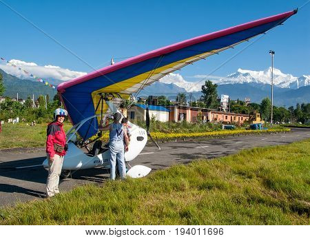 HIMALAYAS, POKHARA, NEPAL. 28 September 2008: Foreign tourist prepares for flight on a hang glider (deltaplan).