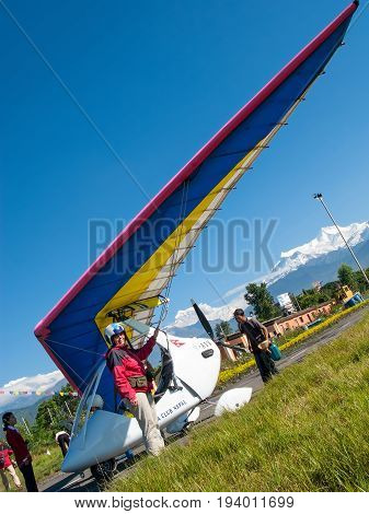 HIMALAYAS, POKHARA, NEPAL. 28 September 2008: Foreign tourist prepares for flight on a hang glider (deltaplan).
