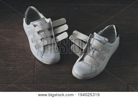 Pair of white worn-out shoes on velcro close-up