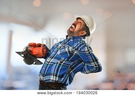 Hispanic worker experiencing back injury while working with circular saw