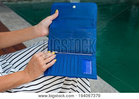 Luxury fashion snakeskin python wallet in woman hands outdoors, shoot near the swimming pool.