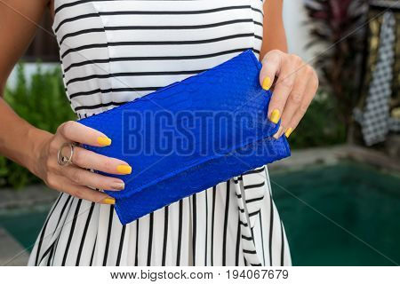 Luxury fashion snakeskin python wallet in woman hands outdoors, shoot near the swimming pool.