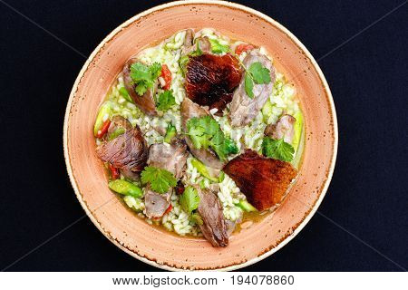 Baked duck served in a plate with rice and green beans and greens dressed with sauce.