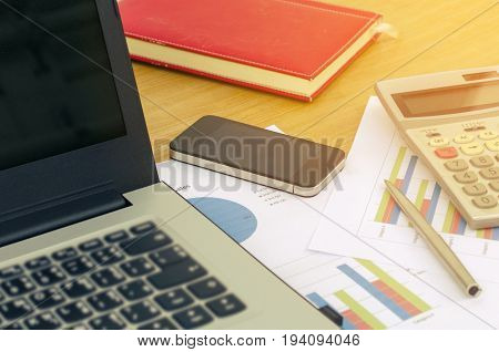 close up business accessories laptop calculator datasheet pen notebook and smartphone on desk financial report saving and economy business concept sunlight effect soft focus selective focus