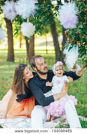 Young mom and dad sitting on the beautiful meadow with my daughter. The concept of a happy family with one child