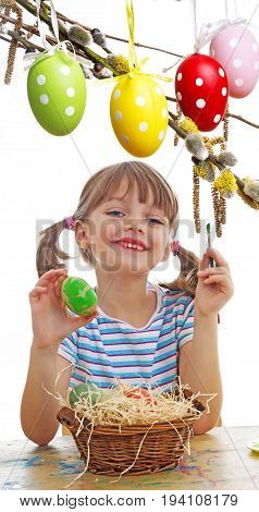 a happy little girl painting easter eggs