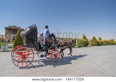 ISFAHAN IRAN - OCTOBER 22 2016 : Iranian tourists sit on carriage during visit the Naghsh-e Jahan Square (Imam Sqaure) UNESCO World Heritage Sites in Isfahan (Esfahan) Iran.