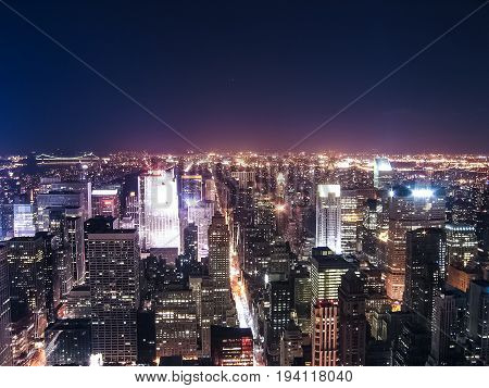 View of night cityscape or skyline of New York City with moon and illuminated buildings from Empire State Building