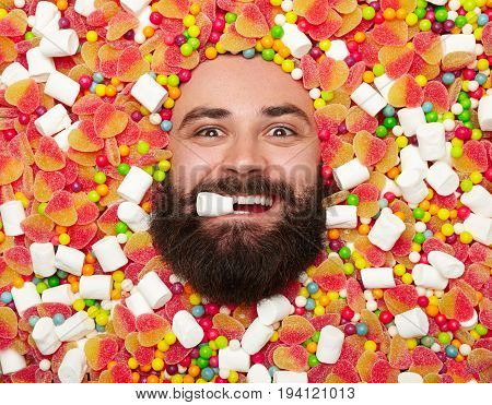 From above shot of expressive bearded man lying in sweets and looking at camera.