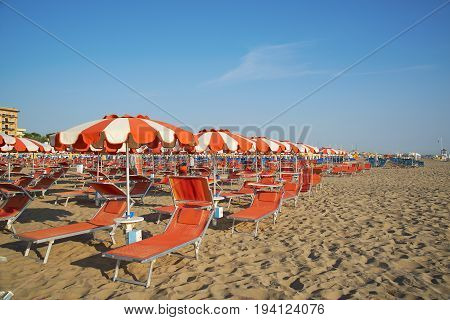 Orange umbrellas and chaise lounges on the beach of Rimini in Italy - the destination in the Adriatic coast of Emilia-Romagna