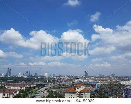 High angle view of Johor Bahru's cityscape on sunny clear day with white clouds over blue skies