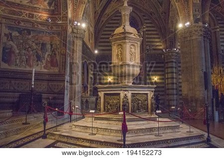Italy Siena - December 26 2016: the view of font in Siena Baptistery with marble tabernacle and statue by Jacopo della Quercia panel by Ghiberti and Faith by Donatello on December 26 2016 in Siena Tuscany Italy.