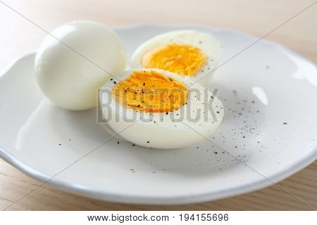 White ceramic plate with hard boiled eggs on light table. Nutrition concept