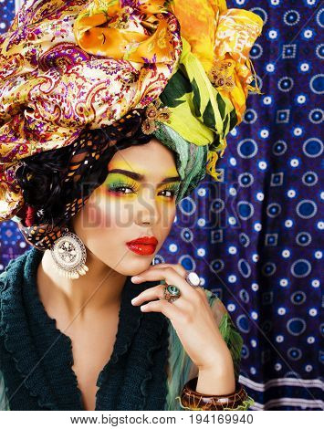 beauty bright woman with creative bright make up, many shawls on head like cubian, ethno look closeup